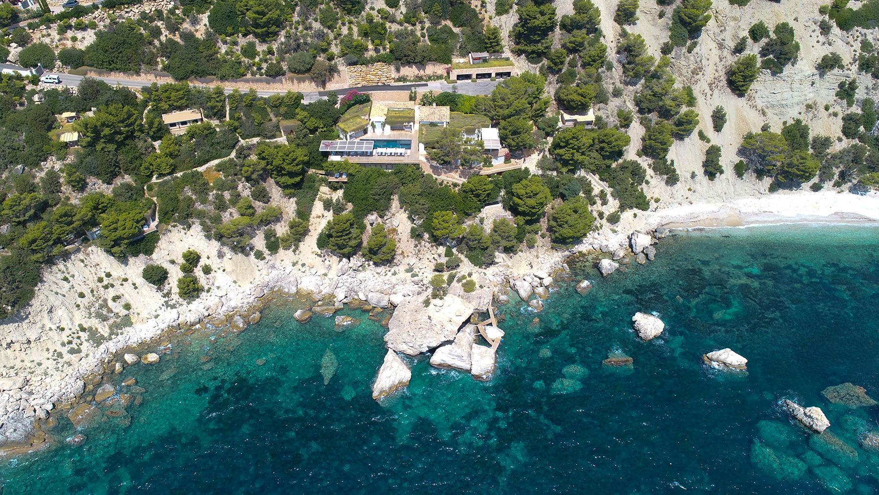 Luxury Ibiza villa surrounded by turquoise Mediterranean coastline and private sea access aerial view