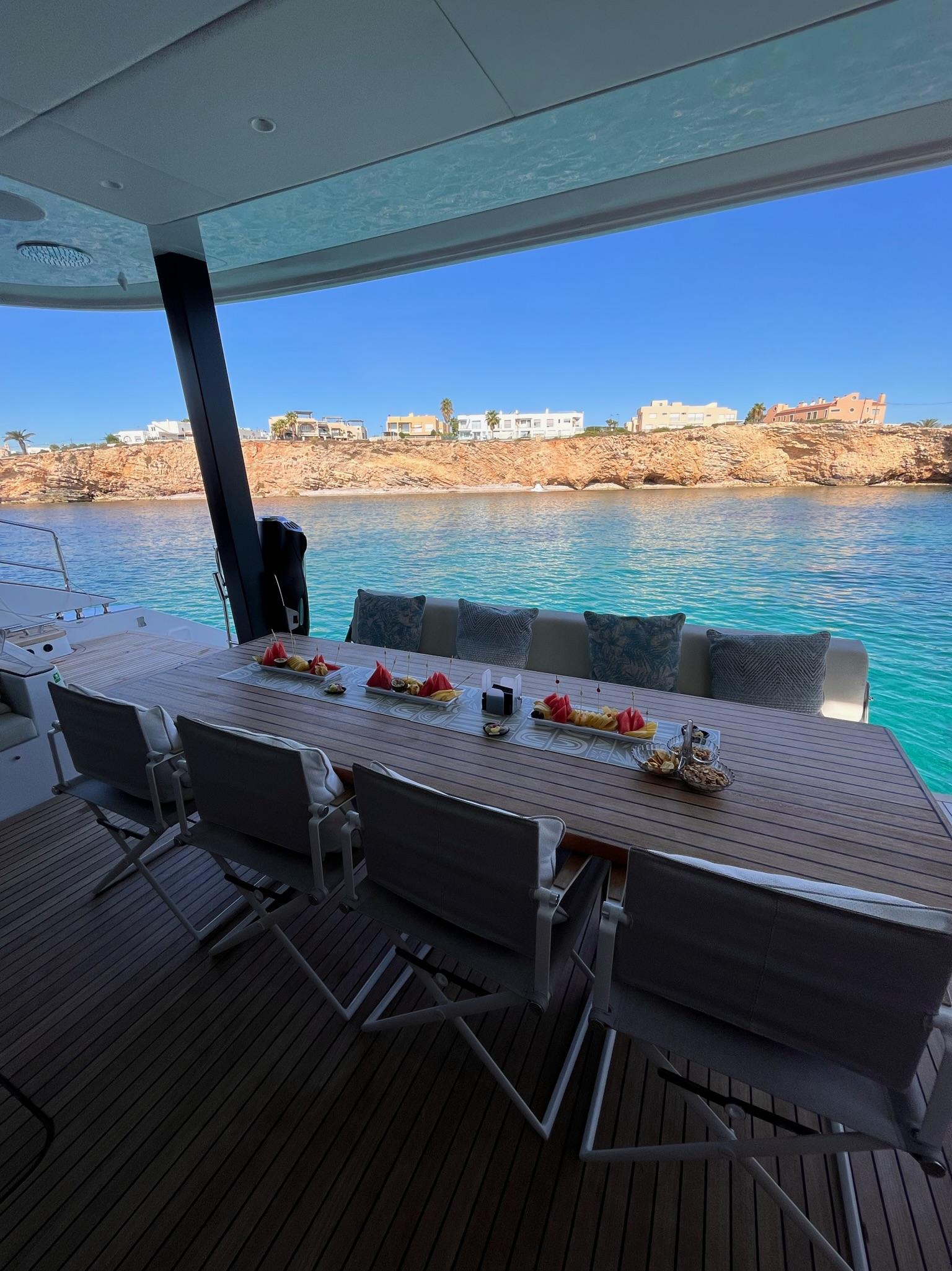Rear outdoor lounge and dining setup aboard Sunreef 70+ catamaran