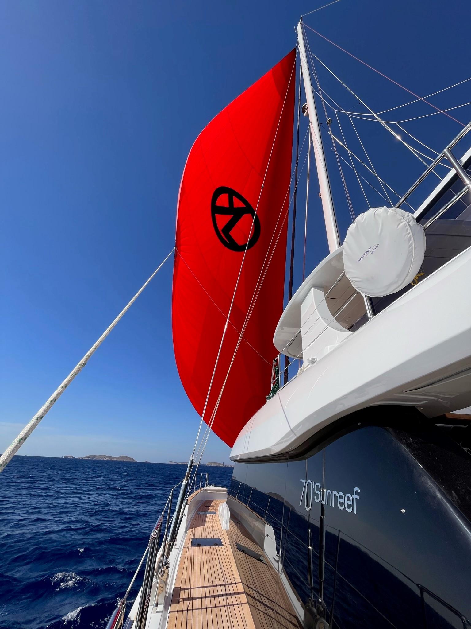 Velero privado navegando en Ibiza con vela roja